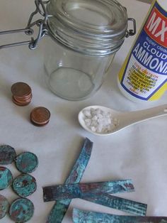 some coins and spoons are sitting on a table next to a jar of paint