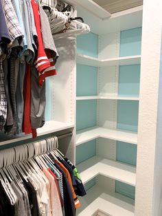 an organized closet with clothes hanging on shelves and folded t - shirts in the corner