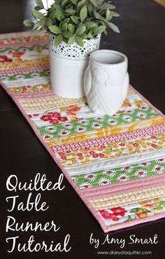 the table runner is made with colorful fabrics and has a potted plant on it