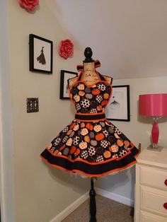 an orange and black dress on a mannequin in front of a wall with pictures