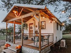 a small white house with lights on the porch