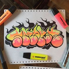 some markers and pens are on top of a piece of paper that has graffiti written on it