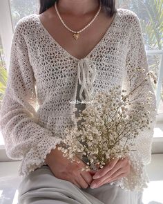 a woman sitting on a window sill holding a bouquet of flowers in her hands