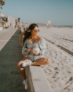 a woman sitting on a wall next to the beach