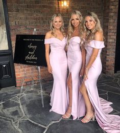 three women in long dresses posing for the camera with one woman wearing a pink dress