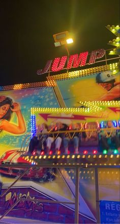 a carnival ride at night with lights on it's sides and people walking around