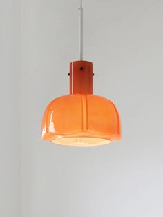 an orange pendant light hanging from a ceiling