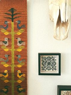 an animal skull is hanging on the wall next to a rug and two framed pictures