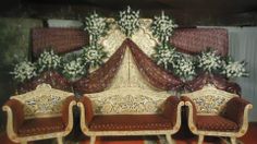 an elaborately decorated couch and chairs in front of a wall with floral arrangements on it