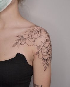 a woman wearing a face mask with flowers on her shoulder and arm tattoo design in black ink