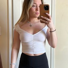 a woman taking a selfie in front of a mirror wearing a white top and black skirt