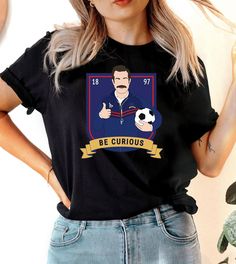 This "Be Curious" design is the perfect, fun Ted Lasso shirt for anyone that loves sports and Ted Lasso! Sports T-shirt With Character Print And Crew Neck, Crew Neck Tops With Character Print For Sports Events, Crew Neck T-shirt With Character Print For Sports Events, Funny Crew Neck Sports T-shirt, Ted Lasso Shirt, Ugly Christmas Sweater Couples, Ted Lasso, Sports Soccer, Be Curious