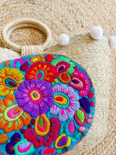 an embroidered purse with pom poms on the handle and handles is sitting on a rug