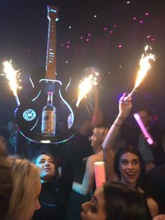 a group of people holding up sparklers in the air at a party with guitars on them