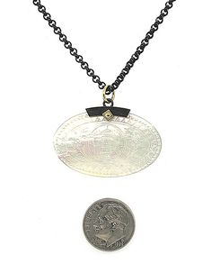 This striking necklace features an antique, mother-of-pearl Chinese gambling counter dating back to the 18th Century. The oval gaming counter is set in a striking blackened silver setting that is accented with an 18k yellow gold rivet and bail. This design is very versatile and looks beautiful worn with both casual and dressy attire!Originally carved in China for export to Britain, gaming counters were used like we would use poker chips. Each was engraved by hand with exquisite detail; different Formal Oval Coin Pendant Jewelry, Luxury Oval Hand Forged Jewelry, Luxury Oval Coin Pendant Necklace, Luxury Oval Pendant Necklace For Collectors, Vintage Ceremonial Jewelry With Coin Pendant, Antique Engraved Coin Necklace Collectible, Vintage Coin-shaped Brass Necklaces, Antique Coin-shaped Tarnish Resistant Necklace, Vintage Tarnish-resistant Coin Necklace