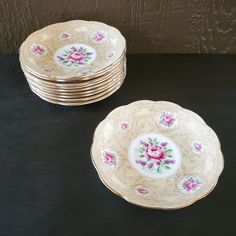 four plates with pink flowers on them sitting next to each other