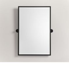 a mirror mounted to the side of a wall with a black frame and metal fittings