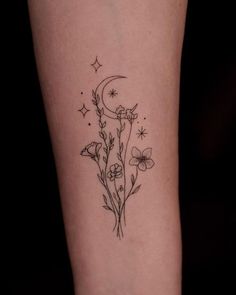 a tattoo on the leg of a woman with flowers and a moon in the background