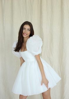 a woman in a short white dress posing for the camera