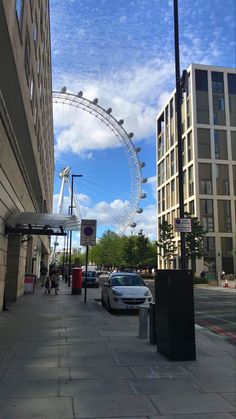 the london eye is in the background as cars are parked on the side of the road