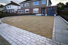 an empty backyard with gravel and brick pavers in the foreground, next to two houses