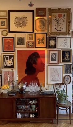 a room filled with lots of framed pictures on the wall next to a wooden table