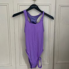 a purple swimsuit hanging on a door hanger in front of a white door