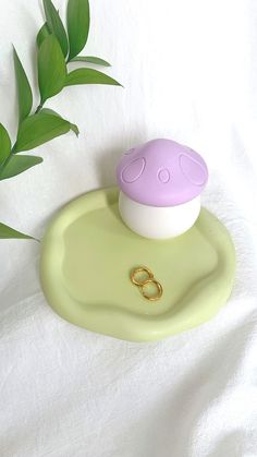 a green plate with a ring on it and a purple object in the middle sitting on a white sheet