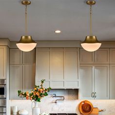 three lights hanging from the ceiling in a kitchen with marble counter tops and white cabinets