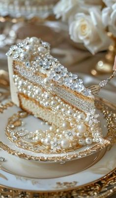 a piece of cake with pearls on it sitting on a plate next to some flowers