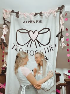 two women standing next to each other in front of a banner