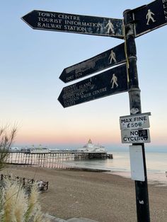 there are many signs on the beach pointing in different directions