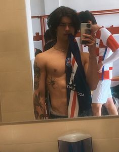 a shirtless man taking a selfie in front of a mirror with his tie around his neck