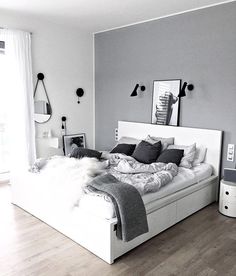 a white bed sitting in a bedroom on top of a hard wood floor next to a window