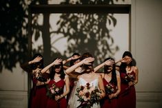 a group of women standing next to each other with their hands on their foreheads