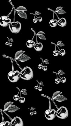 black and white photograph of cherries with leaves on them, set against a black background