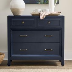 a blue dresser with two white vases on top