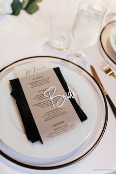 the table is set with black and white place settings, silverware, and napkins