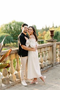 a man and woman standing next to each other on a bridge