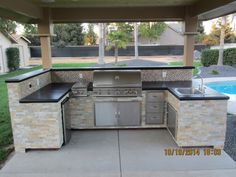 an outdoor kitchen with grill and sink in the middle of a patio area next to a swimming pool