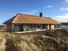 a thatched roof house sits on top of a grassy hill