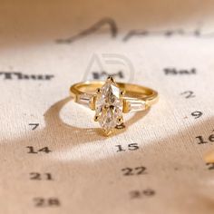 an engagement ring sitting on top of a sheet of paper with numbers in the background