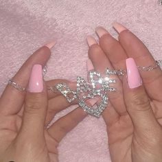 two hands with pink manicures holding a heart shaped diamond brooch in their left hand