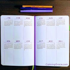 an open calendar book sitting on top of a desk next to markers and pencils