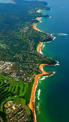 an aerial view of the ocean and beach from above, with houses on either side