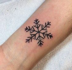 a small snowflake tattoo on the arm