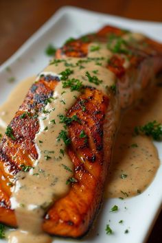 grilled salmon covered in gravy on a white plate