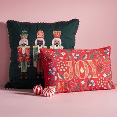 two decorative pillows with nutcrackers on them, one is red and the other is green