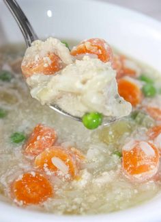 a spoon full of soup with carrots and peas