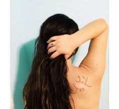 the back of a woman's shoulder with tattoos on it